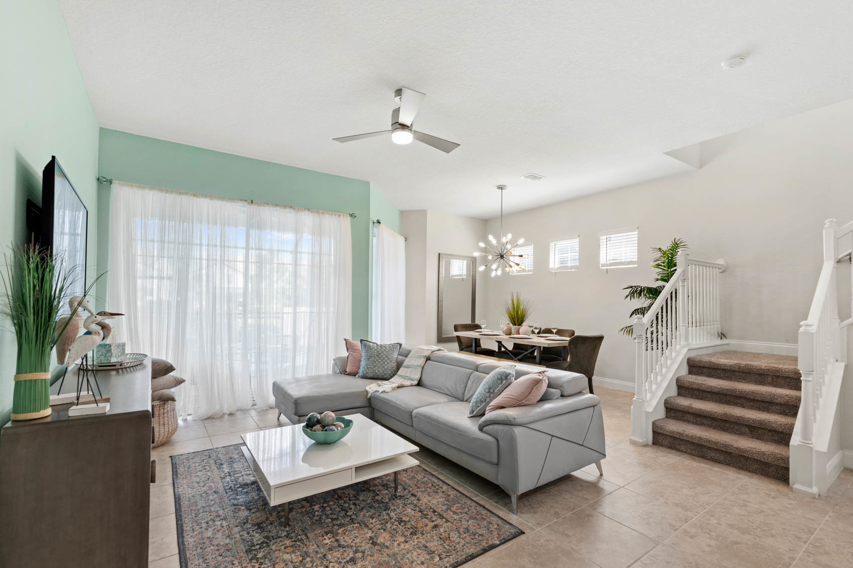 living room with grey couch and white curtains